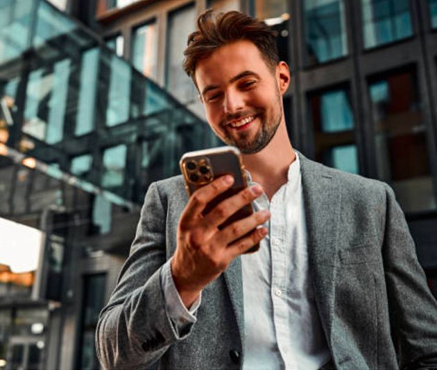 Hombre de negocios sonriendo mientras usa su celular en la ciudad